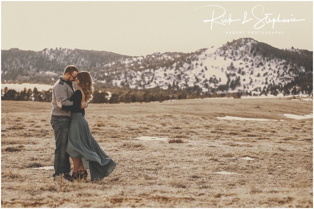 Couple featured in their Cheyenne, WY engagement photos. Wide photo of the couple in front of beautiful Wyoming mountains.